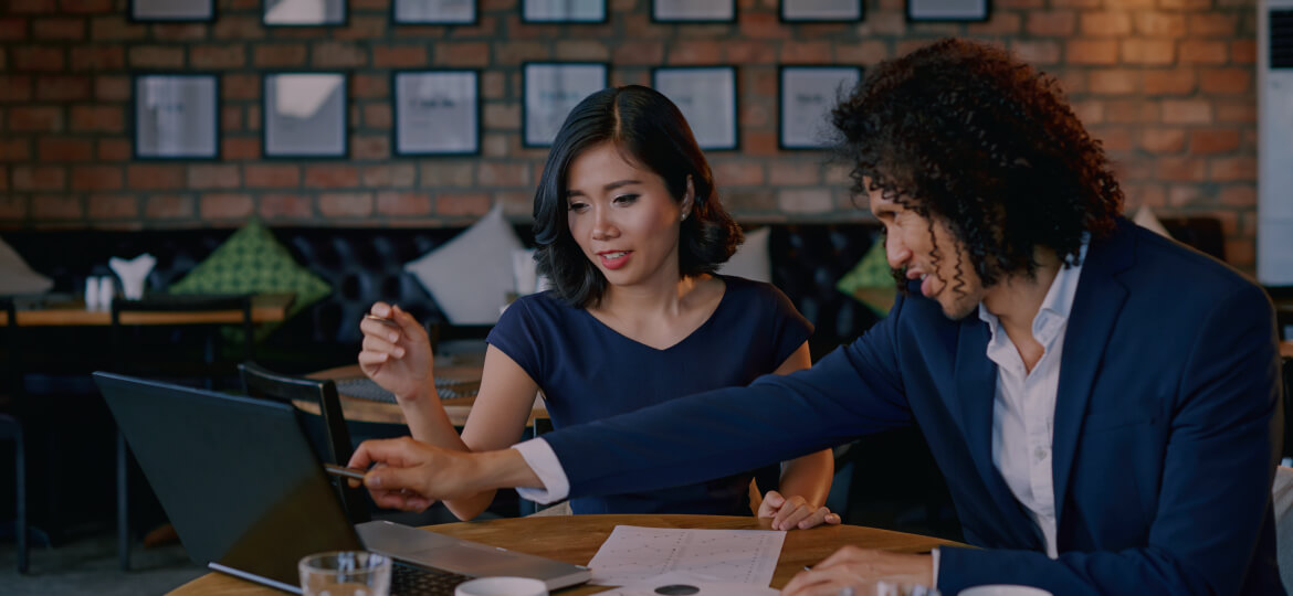 two women collaborating on a laptop in an office environment 