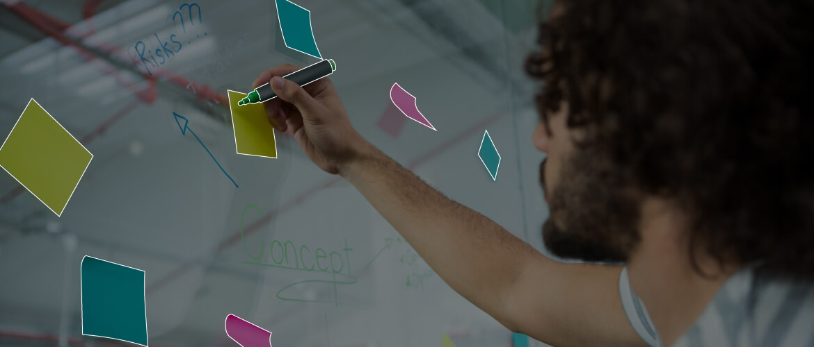 man writing sticky notes on white board